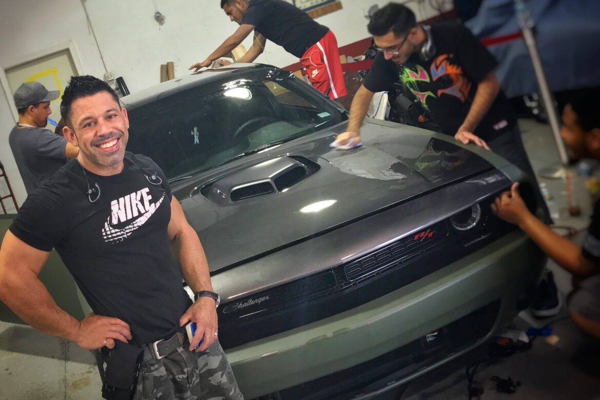 A man standing next to a car in a garage.