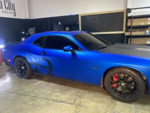 A blue car with black and red paint on the hood.