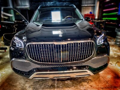 A black car parked in a garage with its hood up.