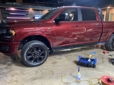 A red truck parked in a garage with a blue hose.