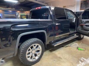 A black truck parked in a garage with its door open.