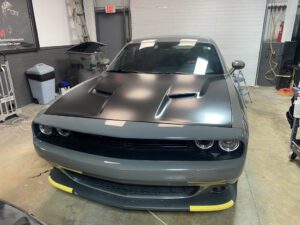 A gray car with yellow trim parked in a garage.