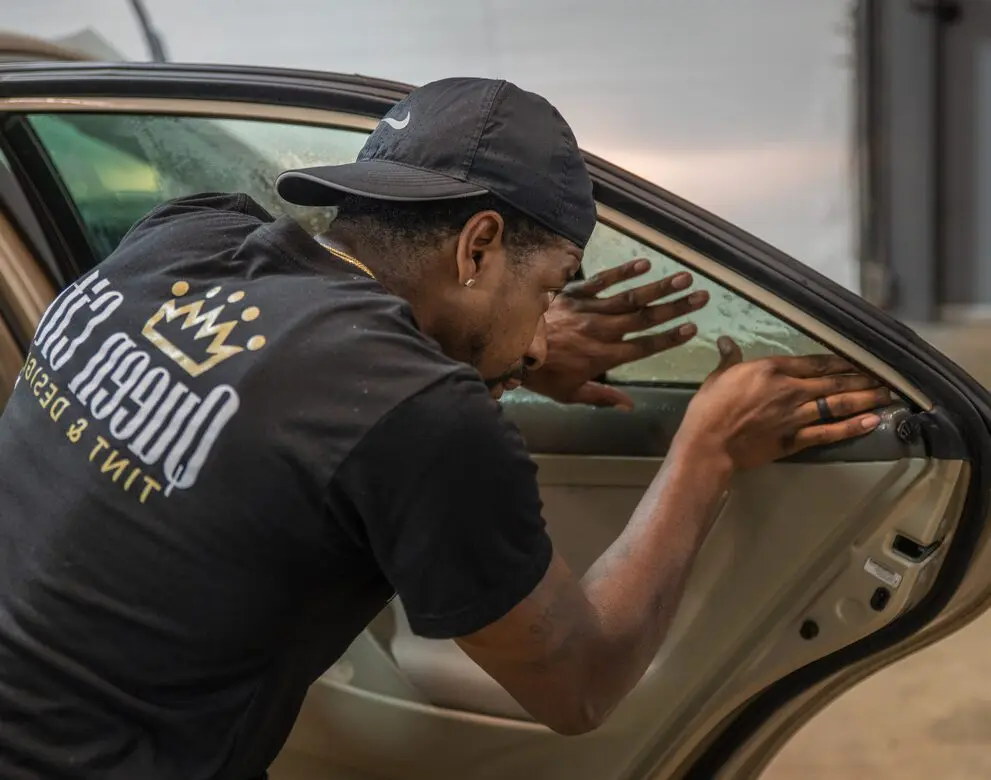 A man in black shirt leaning on car door.