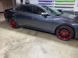 A car parked in the garage with red rims.