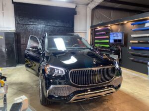 A black car parked in a garage with its door open.