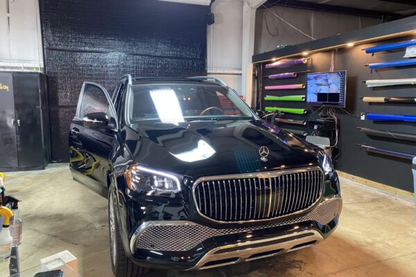 A black car parked in a garage with its door open.