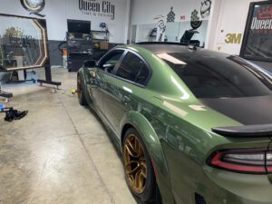 A green car parked in a garage with other cars.