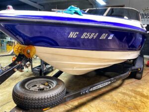 A boat is parked on the trailer in a garage.