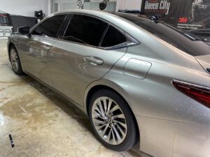 A silver car parked in the garage with its door open.