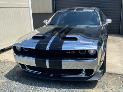 A silver car with black stripes on the hood.