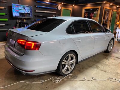 A white car parked in a garage with its lights on.