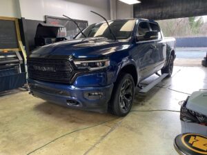 A blue truck parked in a garage with its doors open.