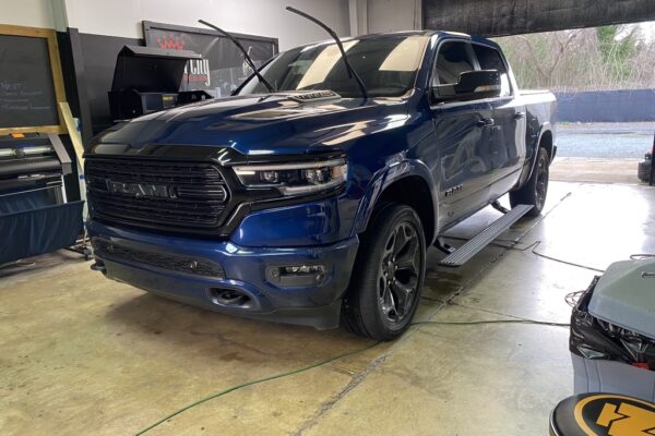 A blue truck parked in a garage with its doors open.