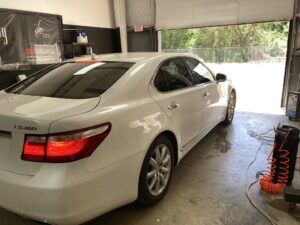 A white car parked in the garage with its door open.