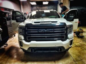 A white truck parked in a garage with other vehicles.