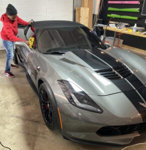 A woman is putting the hood on a car.