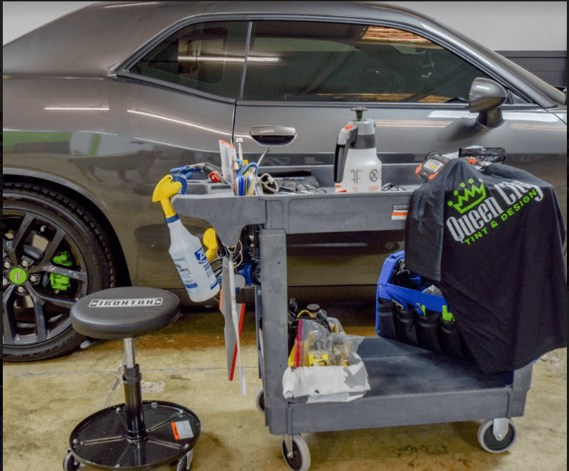 A car is parked in the garage with tools on it.