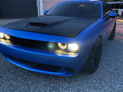 A blue car parked in front of a garage.