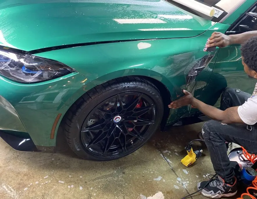 A man is working on the side of his car.