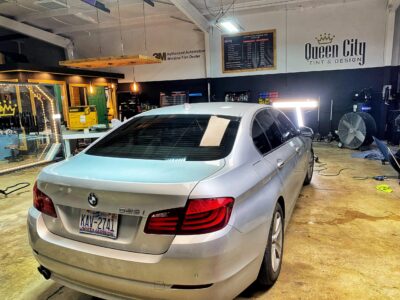 A silver car parked in a garage with other cars.