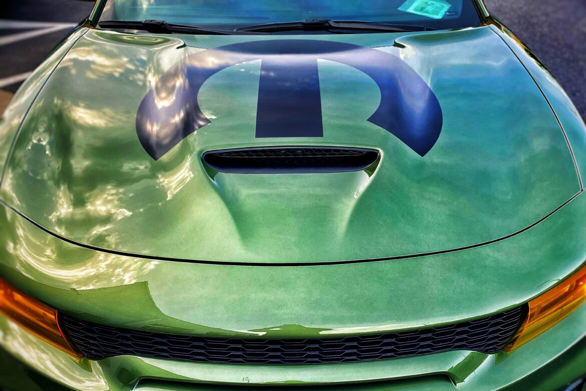 A green car with blue stripes on the hood.