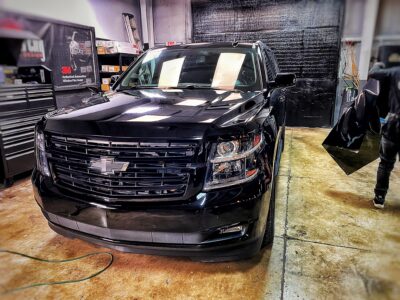 A black truck parked in a garage with its hood up.