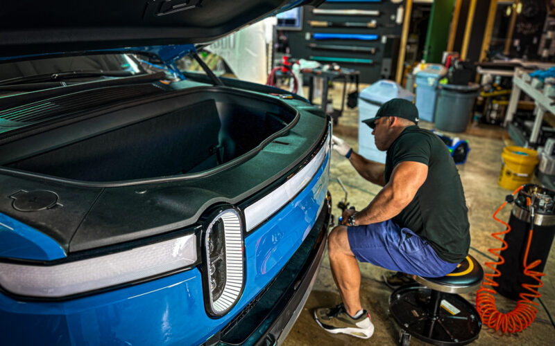 A man working on the hood of his car.