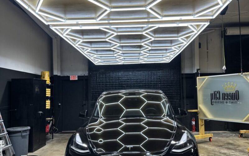 Black Tesla in hexagonal-lit garage.